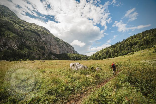 Hiking u Nacinalnom parku Sutjeska, covjek u crvenoj majici seta planinskim puteljkom, planine oko njega